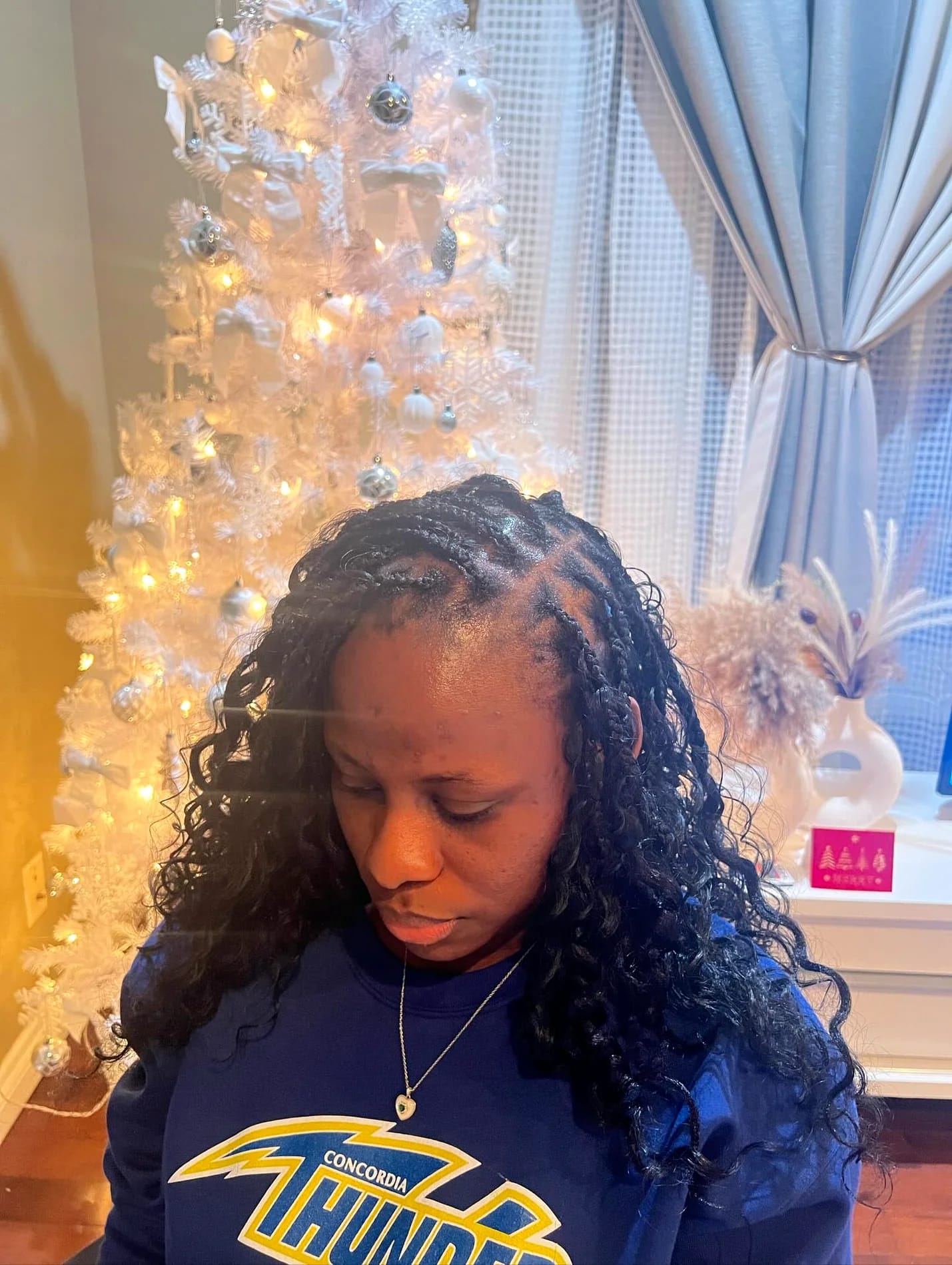 Shoulder-length braids with loose curly strands, client looking down