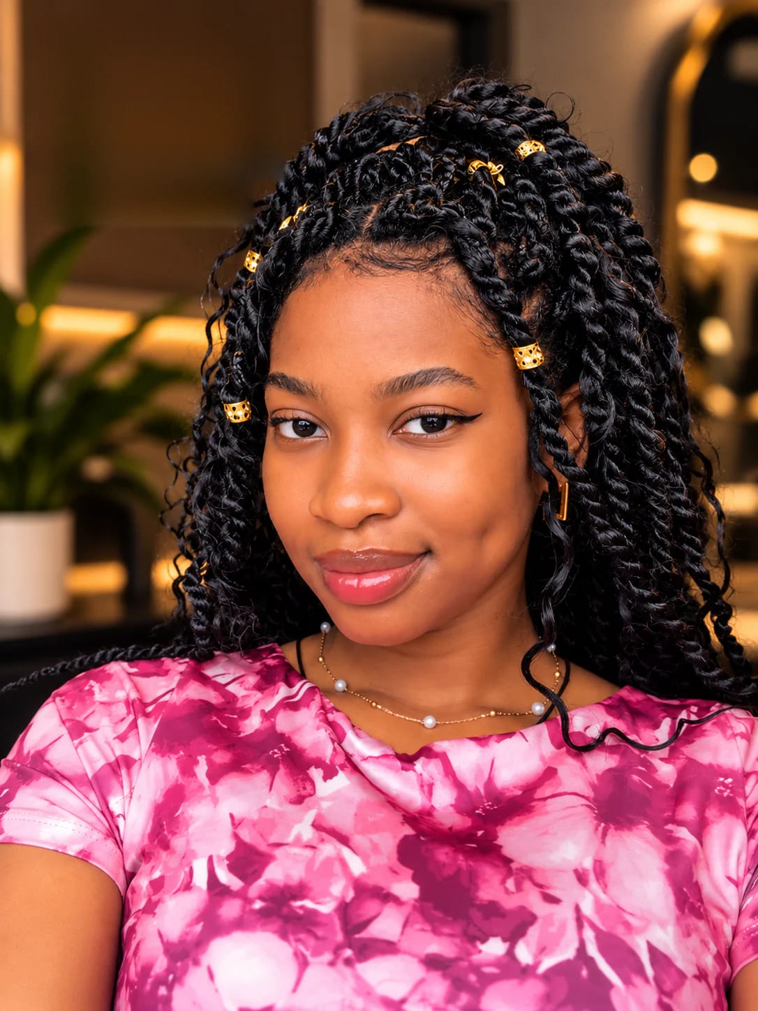 Long black twists with gold hair cuffs, in a warmly lit salon